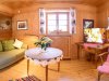 Wohnzimmer mit Fernseher und Sofa in Hütte In einem Holzhaus steht ein Sofa und ein Tisch vor einem Fernseher. Es gibt Fenster mit Vorhängen und Dekorationen an den Wänden.