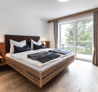 Ansicht vom Schlafzimmer mit Doppelbett und Ausgang auf den Balkon.