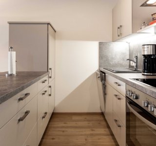 Bild der Küche mit Herd, Oden, Kühlschrank, Waschbecken und Kaffeemaschine.