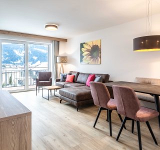 Helles Wohnzimmer mit Esstisch, Stühlen und Sofa.