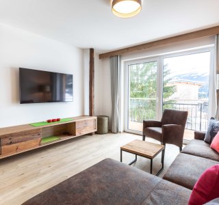 Wohnzimmer mit Sofa, Fernseher und Balkontüre.