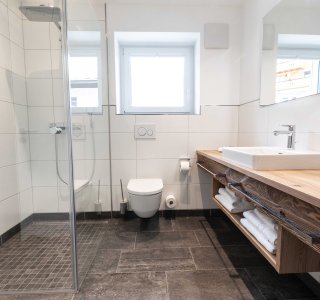 Helles Badezimmer mit Dusche, WC und Waschbecken.