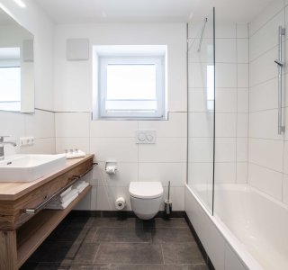 Badezimmer mit Waschbecken, WC, Badewanne und integrierter Dusche.