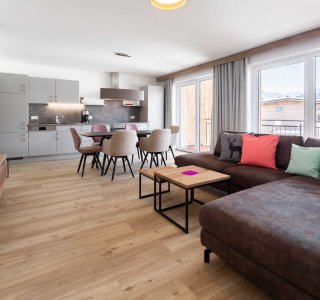 Wohn-Esszimmer mit Sofa, Fernseher, Esstisch und Stühlen und der Küchenzeile.