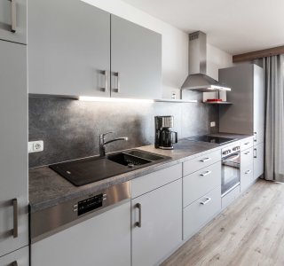 Bild von einer der Küchenzeilen mit Herd, Kaffeemaschine, Backofen und Kühlschrank.