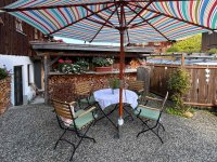 Gemütlicher Gartenplatz mit Sonnenschirm und Stühlen