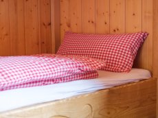 Im Hüttenbett aus hellem Holz lässt es sich gut ausruhen.