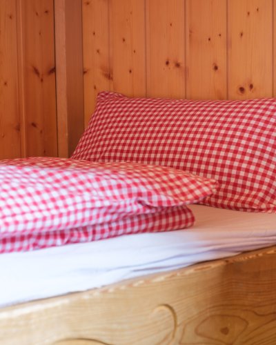 Im Hüttenbett aus hellem Holz lässt es sich gut ausruhen.