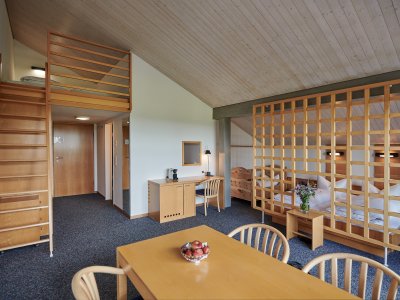 Zwei Erwachsene mit drei Kindern können im Familienzimmer Buching entspannt und mit ausreichend Platz schlafen und verweilen.