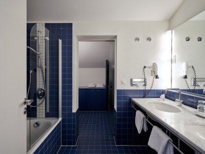 Zum Familienzimmer Buching gehört auch ein großzügiges Bad mit zwei Waschbecken, Badewanne und Dusche