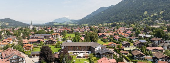 Drohnenperspektive auf das Hotel Exquisit mit Bergpanorama