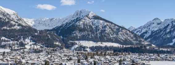 Eine ruhige Winterlandschaft mit schneebedeckten Bergen und einem kleinen Dorf, umgeben von Natur.