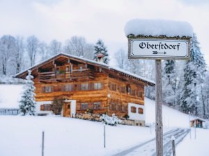 Ein rustikales Holzhaus in Oberstdorf, umgeben von Schnee und verschneiten Bäumen an einem klaren Wintertag.