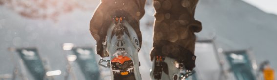 Eine Person wandert im Schnee, während die Sonne am Himmel scheint. Der Schnee glitzert in der Winterlandschaft.