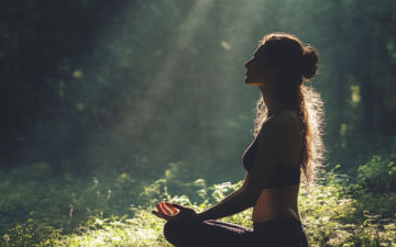 Enspante Yogapose im Wald direkt in den Sonnenstrahllen