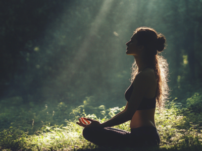 Enspante Yogapose im Wald direkt in den Sonnenstrahllen
