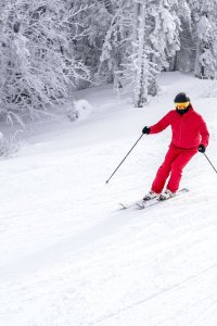 Skier-ina-red-costume-skiing-down-slope-near-trees