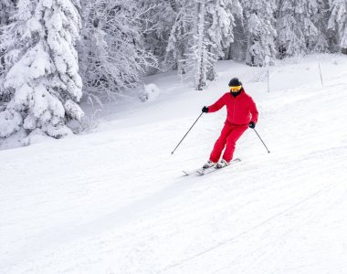 Skier-ina-red-costume-skiing-down-slope-near-trees