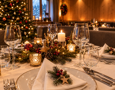 Festlich gedeckter Weihnachtstisch mit Kerzenlicht, Tannengrün und weihnachtlicher Dekoration. Warme Lichter, elegante Tischdekoration und eine gemütliche Atmosphäre schaffen den perfekten Rahmen für einen besinnlichen Heiligabend und genussvolle Weihnachtsmomente in den Bergen.