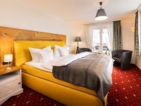 Hotelzimmer mit gelbem Bett und Stühlen