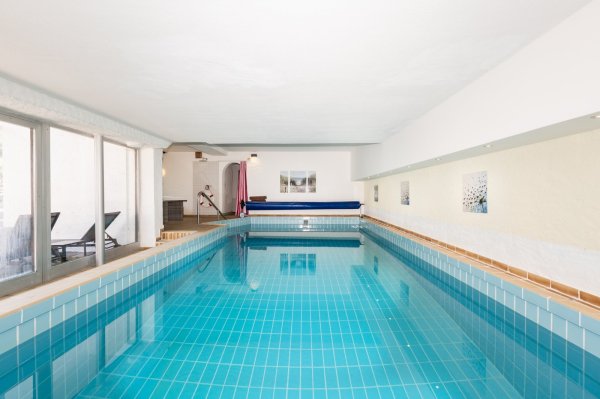 Schwimmbad in einem Innenraum Das Schwimmbad ist drinnen. Das Wasser ist blau. Es gibt Liegen neben dem Becken. Es ist ein ruhiger Ort.