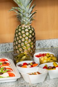 Ein Tisch mit frischem Obst, Gemüse und verschiedenen Snacks. Es gibt Tomaten, Gurken, Oliven und Joghurt in Schalen.