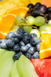 Ein Obstteller zeigt eine Vielzahl von Früchten wie Melonen, Trauben und Orangen. Das Bild zeigt auch eine schöne Anordnung der Früchte.