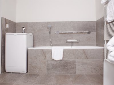 Das moderne Bad verfügt über Badewanne, ebenerdige Dusche, Toilette, Waschbecken und ist sogar mit einer Waschmaschine ausgestattet. Die komplette Badausstattung ist rollstuhlgerecht.