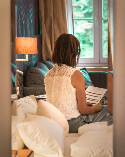 Zeit für Ruhe: Entspannung im stilvollen Hotelzimmer Erholung pur im Hotel Mohren in Oberstdorf: In stilvollem Ambiente entspannen Gäste im komfortablen Zimmer und blättern entspannt in der Gästemappe. Perfekt für eine Auszeit im Allgäu mit Wohlfühlgarantie.