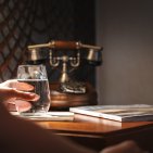 Stilvolle Details im Hotel Mohren in Oberstdorf: Am Nachttisch mit Retro-Telefon genießen Gäste entspannte Momente bei einem Glas Wasser und gemütlicher Lektüre. Perfekt für erholsame Urlaubstage im Allgäu.