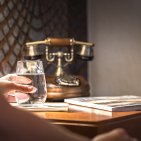 Ihr Rückzugsort voller Wohlgefühl Stilvolle Details im Hotel Mohren in Oberstdorf: Am Nachttisch mit Retro-Telefon genießen Gäste entspannte Momente bei einem Glas Wasser und gemütlicher Lektüre. Perfekt für erholsame Urlaubstage im Allgäu.