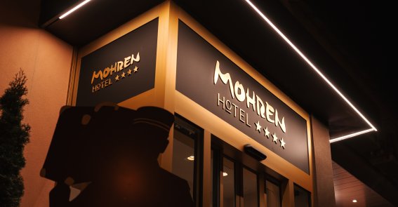 Der beleuchtete Eingangsbereich des Hotel Mohren Oberstdorf präsentiert sich bei Nacht modern und einladend. Die klare Architektur, das markante Hotellogo und die stilvolle Außenbeleuchtung unterstreichen den hochwertigen Charakter des Hotels im Zentrum von Oberstdorf.