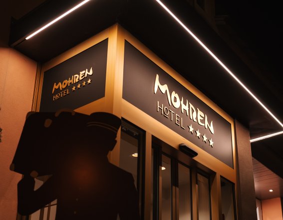 Der beleuchtete Eingangsbereich des Hotel Mohren Oberstdorf präsentiert sich bei Nacht modern und einladend. Die klare Architektur, das markante Hotellogo und die stilvolle Außenbeleuchtung unterstreichen den hochwertigen Charakter des Hotels im Zentrum von Oberstdorf.