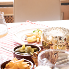 Jemand schenkt in ein Glas Bier ein und auf dem Tisch steht verschiedenen Essen.