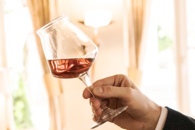 Ein Mann hält ein Glas mit dunklem Bier und schwenkt es.