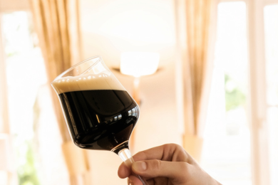 Hand mit Biertulpe Eine Hand hält eine Biertulpe, gefüllt mit dunklem Craftbier in die Höhe.