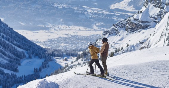 HM Oberstdorf-im-Winter Skifahrer blicken vom Berg auf das verschneite Oberstdorf.