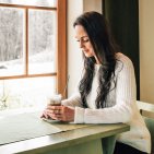 Geniet van een ontspannen wintervakantie in Hotel Oberstdorf in de Allgäu. Een vrouw geniet van een rustig moment met een warm drankje in Hotel Oberstdorf – ontspannende wintermomenten met uitzicht op de besneeuwde natuur van de Allgäu.