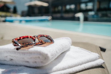 Sonnenbrille auf Handtüchern am Pool im Hotel Oberstdorf mit Wellnessgefühl Wellnessurlaub im Allgäu mit Pool, Kosmetik und besonderen Saunen. Im Hotel Oberstdorf bekommen Sie die perfekte Portion Me-Time und selfcare Momente!