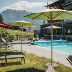 Beheizter Außenpool des Hotel Oberstdorf mit Sonnenliegen und Blick auf die Allgäuer Berge – entspannte Wellnessmomente unter freiem Himmel.