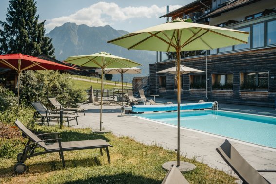 Außenpool mit Bergblick im Hotel Oberstdorf im Allgäu Beheizter Außenpool des Hotel Oberstdorf mit Sonnenliegen und Blick auf die Allgäuer Berge – entspannte Wellnessmomente unter freiem Himmel.