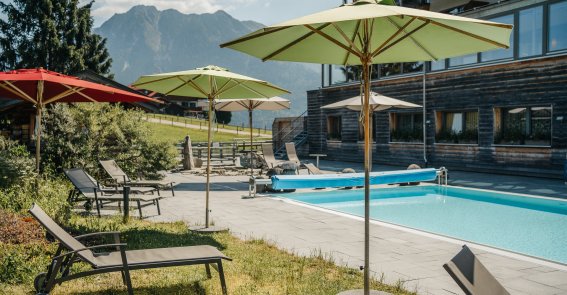 Außenpool mit Bergblick im Hotel Oberstdorf im Allgäu Beheizter Außenpool des Hotel Oberstdorf mit Sonnenliegen und Blick auf die Allgäuer Berge – entspannte Wellnessmomente unter freiem Himmel.
