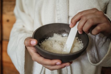 Gast hält Schale mit Peeling-Salz für Wellnessanwendung im Hotel Oberstdorf Freuen Sie sich auf Ihren besonderen Wellnessurlaub im Allgäu mit besten Wellnessbehandlungen im Wellnesshotel in Oberstdorf!