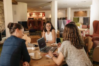 Drei Frauen bei einer Besprechung in der Lounge des Hotel Oberstdorf Im Tagungshotel Oberstdorf treffen moderne Ausstattung und inspirierende Umgebung aufeinander. Perfekt für Tagungen, Workshops und Seminare, die effektives Arbeiten mit Wohlfühlatmosphäre verbinden.