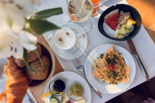 Liebevoll gedeckter Frühstückstisch im Hotel Oberstdorf mit Croissant, Eierspeise, Obst, Kaffee und Säften für einen genussvollen Start in den Tag.
