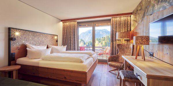 Gemütliches Hotelzimmer mit Holzbett, Balkon und Bergblick in Oberstdorf Mit Bergblick und Balkon sind die Doppelzimmer Allgäu Style Superior im Hotel Oberstdorf ausgestattet.