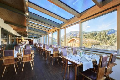 Vom lichtdurchfluteten Wintergarten aus, blicken Sie direkt in ins Grüne. Dieser ist einer von vier ganz unterschiedlich gestalteten Räume im Restaurant im Hotel Oberstdorf.