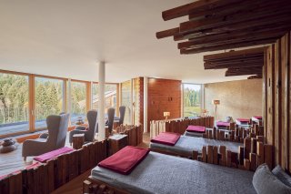 Gemütlicher Panorama-Ruheraum in der Alpen Wellnesswelt des Hotel Oberstdorf mit großen Fenstern, Liegeflächen und Blick ins Grüne.