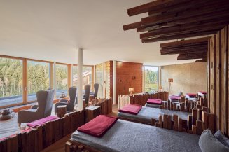 Gemütlicher Panorama-Ruheraum in der Alpen Wellnesswelt des Hotel Oberstdorf mit großen Fenstern, Liegeflächen und Blick ins Grüne.