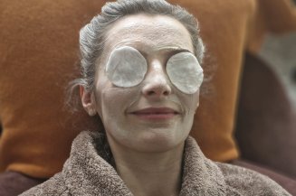 Gesichtsmaske Frau bekommt im Wellnessbereich eine Gesichtsmaske